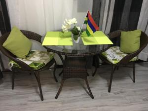 a table with chairs and a vase of flowers on it at The Octagon wing A in Beau Vallon