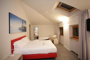 Habitación de hotel con cama blanca y banco rojo en StraVagante Hostel & Rooms en Verona