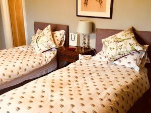 a bedroom with two beds and a table with a lamp at Hollow Meadow House in Priors Marston