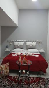 una camera con un letto con una coperta rossa e un tavolo di Five house a Napoli