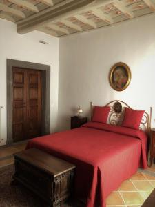 1 dormitorio con cama con sábanas rojas y puerta de madera en Il Rifugio del Cavaliere, en Vetralla