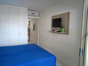 a bedroom with a blue bed and a flat screen tv at Flat Monte Castelo Gravatá in Gravatá