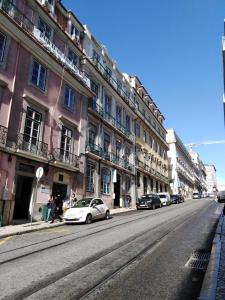 una calle de la ciudad con coches estacionados frente a los edificios en Lisbon Glamorous House en Lisboa