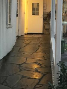 a stone walkway leading to a white door at Holsthuset Losji in Grimstad
