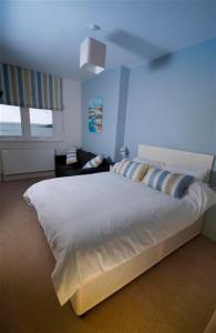 a bedroom with a white bed and a blue wall at The Paris Hotel in Coverack