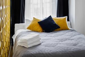 a bed with yellow and blue pillows on it at Grand Theatre Prime Apartment in Warsaw