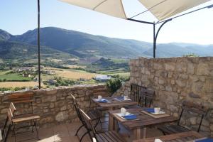 a patio with tables and chairs with mountains in the background at La Clavelière in Saint-Auban-sur-lʼOuvèze