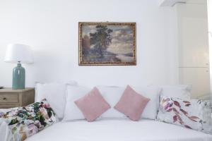 Charming and cosy apartment في بولونيا: سرير ابيض مع مخدات وصوره على الحائط