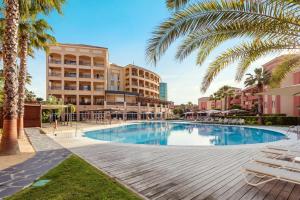 a swimming pool with palm trees and buildings at Ama Islantilla Resort in Islantilla