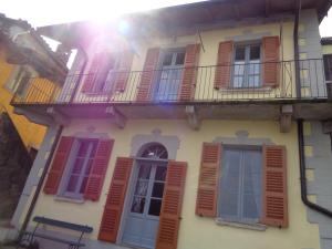 un edificio con ventanas de contraventanas rojas y un banco en La Ca' Vegia en Stresa