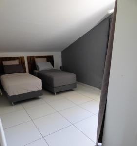 sypialnia z 2 łóżkami i białą podłogą wyłożoną kafelkami w obiekcie Bel appartement spacieux w mieście Étang-Salé les Bains
