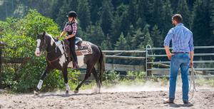 una mujer monta un caballo mientras un hombre mira en Seebacher Apartments, en Sarentino