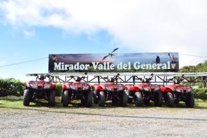 un grupo de cuatro ATV estacionados bajo una valla publicitaria en Mirador Valle del General, en La Ese