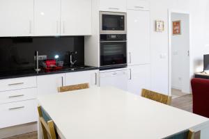 a kitchen with white cabinets and a white table with chairs at Flamingo House - historic center free garage in Évora