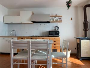 cocina con armarios blancos, mesa y sillas en Trentino Apartments - Casa Aurora en Folgaria