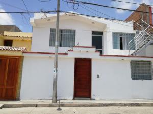 una casa blanca con puertas marrones en una calle en CASA F'BALUA, en Tacna