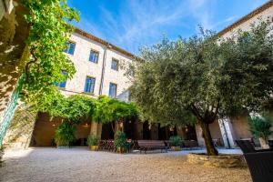 a courtyard of a building with trees and benches at Le Cloître des Dominicains in Buis-les-Baronnies