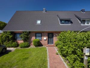 a red brick house with a black roof at Düne 6 in Sankt Peter-Ording