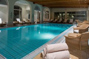 uma grande piscina com cadeiras e cadeiras num hotel em Hôtel Ermitage em Évian-les-Bains