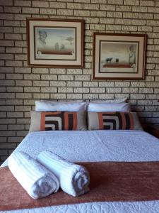 a bedroom with a bed with two pictures on a brick wall at Die Plasie on-suite rooms in Hartbeespoort