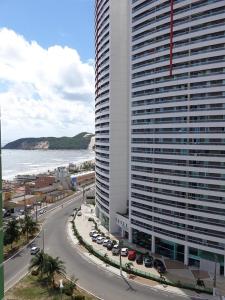 un edificio alto junto al océano con una calle en DUNA BARCANE RESIDENCE, en Natal