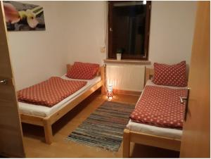 Cette chambre comprend 2 lits avec des oreillers rouges et une fenêtre. dans l'établissement Ferienwohnung Ranch, à Meckenbeuren 2 autres photos