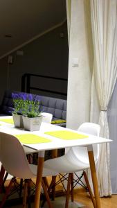 ビャウィストクにあるApartament Bakossaの白い椅子と紫の花が飾られた白いテーブル