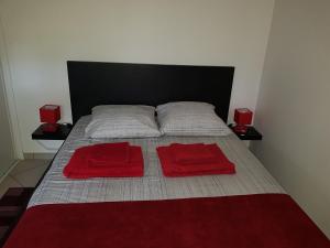 a bed with two red towels on top of it at A L'Orée du Bois in Rillieux