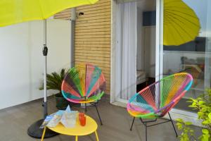 dwa krzesła i stół z parasolem na ganku w obiekcie LA LOCANDA DELL'ARTE-DE GASPERI w mieście Napoli