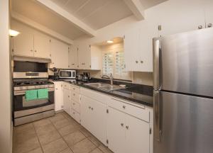a kitchen with white cabinets and a stainless steel refrigerator at Sunset Inn Pacific Grove in Pacific Grove