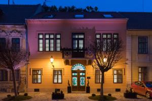 różowo-żółty budynek z drzwiami w nocy w obiekcie Boutique hotel Tvrđa w mieście Osijek