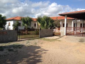 a fence in front of a house with palm trees at Repouso do Mar Residence in Aracati