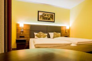 a hotel room with two beds and a table at Naam Hotel & Apartments Frankfurt City-Messe Airport in Frankfurt/Main