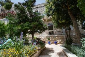 a garden with flowers and trees in front of a building at The Pearl in Talbyeh in Jerusalem