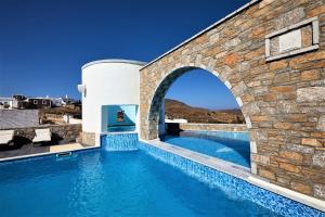 an infinity pool with an arch in a stone wall at Vigla Hotel in Aegiali