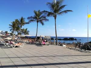 una spiaggia con palme e persone sedute su sedie di Apartamento Valeria a Puerto del Carmen