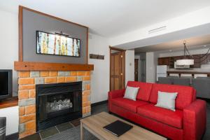 a living room with a red couch and a fireplace at Tour des Voyageurs in Mont-Tremblant