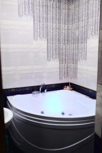 a bath tub in a bathroom with a chandelier at Classic Hotel in Pyatigorsk