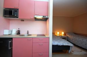 una pequeña cocina con armarios rosados y una cama en Piibutopsu Holiday House en Nasva