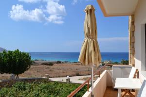 a patio with an umbrella and the ocean at Romantica Apartments in Falasarna