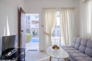 ein Wohnzimmer mit einem Sofa, einem TV und einem Tisch in der Unterkunft Beautiful one bed apartment in Paphos in Paphos City