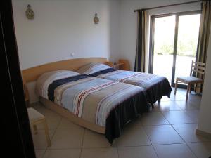 a bedroom with a bed and a window and a chair at Esti Chamaco - Lagos in Lagos