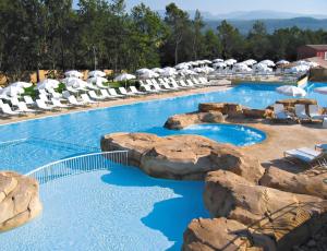 a swimming pool with rocks and chairs in a resort at Lagrange Vacances Domaine de Fayence in Fayence