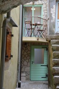 a building with a green door and a balcony at Andrijana in Vrbnik