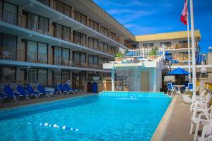 a pool at a hotel with blue chairs and a hotel at Roman Holiday Resort in North Wildwood