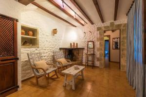 ポリェンサにあるCuixach - Stone mallorcan villa in Pollensaの石壁のリビングルーム(椅子、テーブル付)