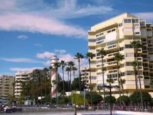a building with a lighthouse in front of palm trees at Polo Apartments 8B in Marbella