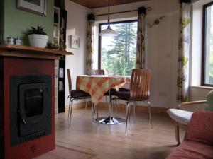 sala de estar con mesa, sillas y chimenea en Drombrow Cottage en Bantry