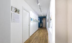 a hallway with white walls and paintings on the walls at OTTO Rooms & Photogallery in Rome