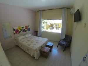 Un dormitorio con una cama y una ventana y una silla. en Casa do Monge Apartments, en Ilhabela